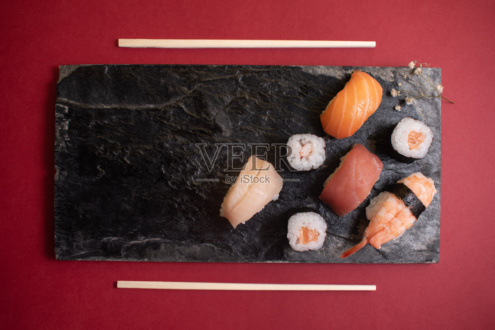 在黑色盘子上放上不同的寿司和一朵小花照片摄影图片