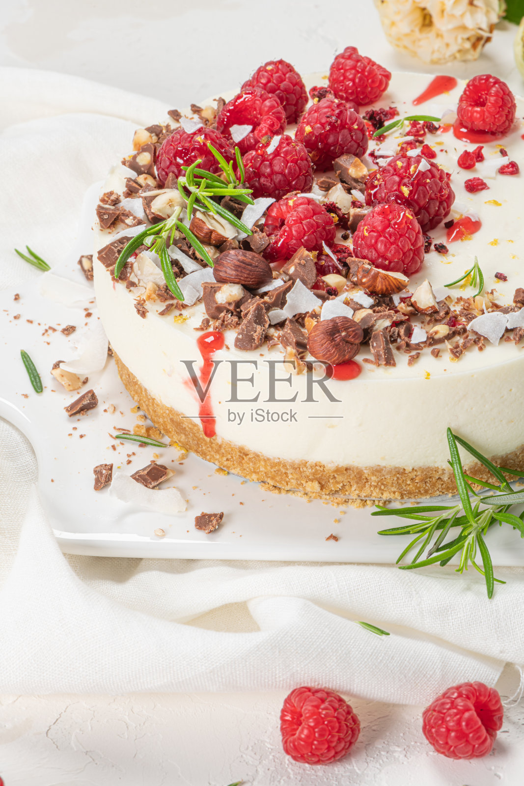 厨房台面上放着覆盆子、巧克力、榛子和迷迭香叶的芝士蛋糕照片摄影图片