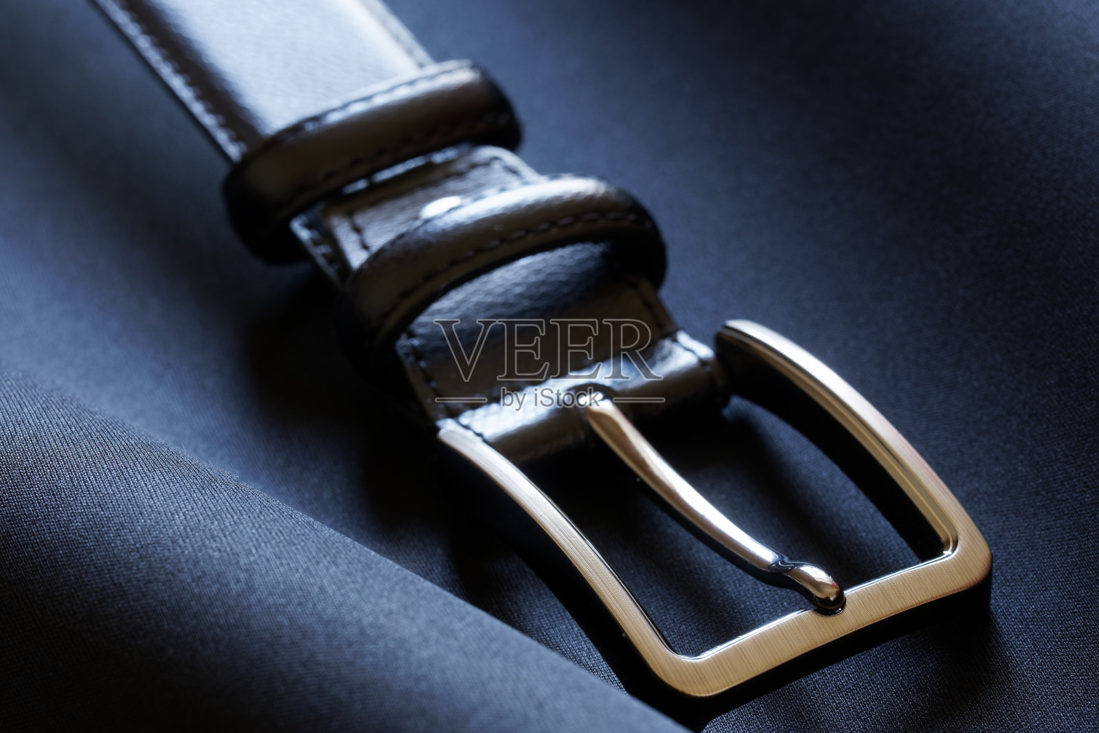 一个抛光的金属皮带扣在深蓝色的纺织背景上。宏照片摄影图片