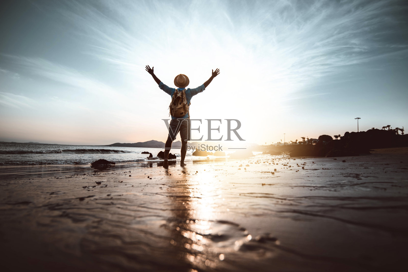 日落时分，在海滩上举起双手的男人——幸福和幸福的概念照片摄影图片