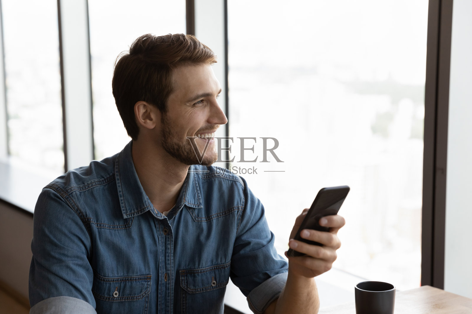 微笑的男人用手机看远处思考照片摄影图片