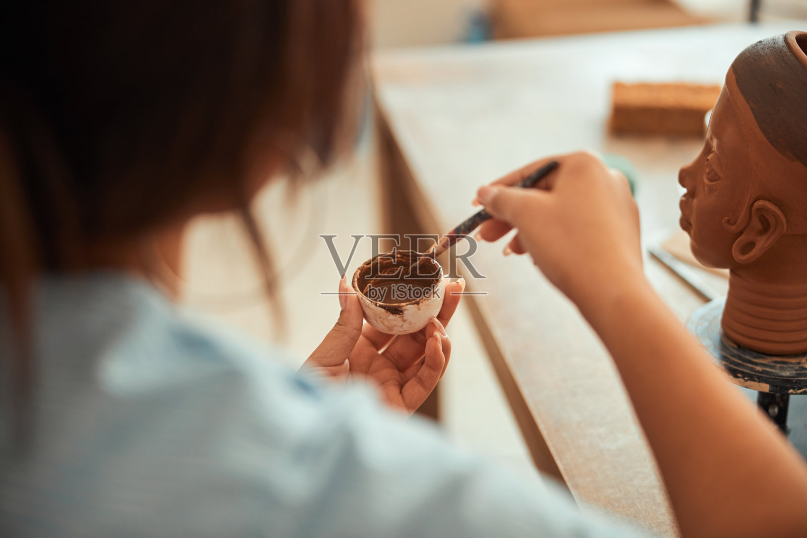 年轻女子拿着画笔和碗，碗里有棕色的颜料照片摄影图片