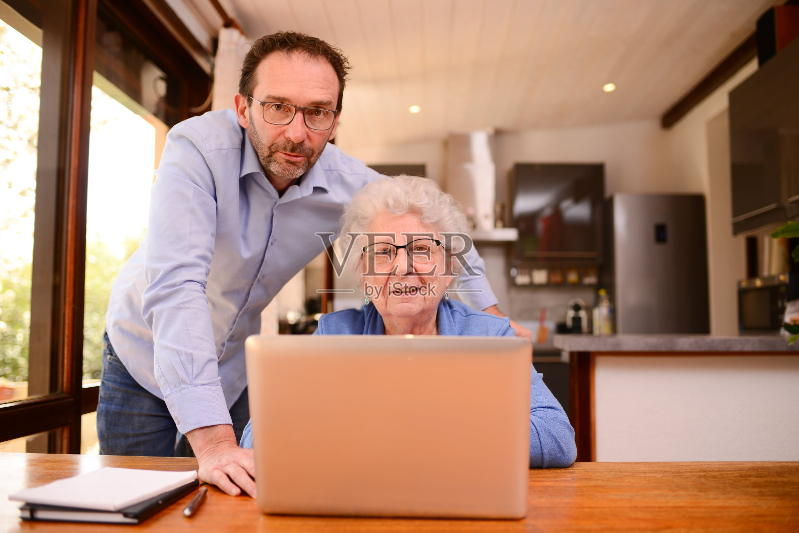 成熟的男人在家里帮助年长的妇女做文书工作和上计算机网络课照片摄影图片