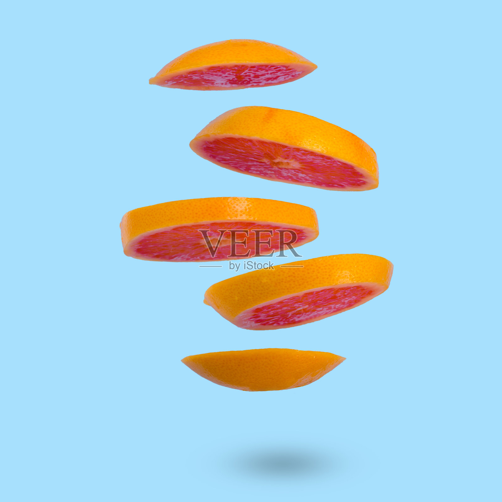 在浅蓝色的背景下漂浮着成熟的葡萄柚。照片摄影图片