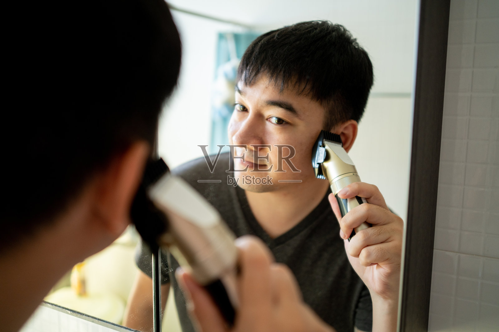 亚洲男人在家里剪头发，自己剪吧。照片摄影图片