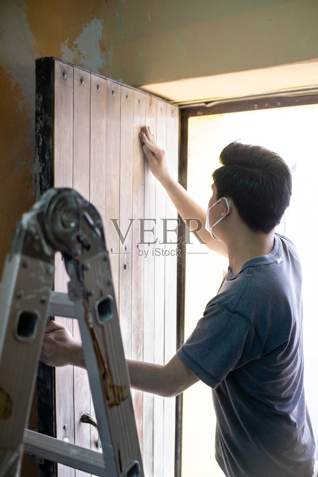 一名男子将砂纸递到木门上油漆照片摄影图片