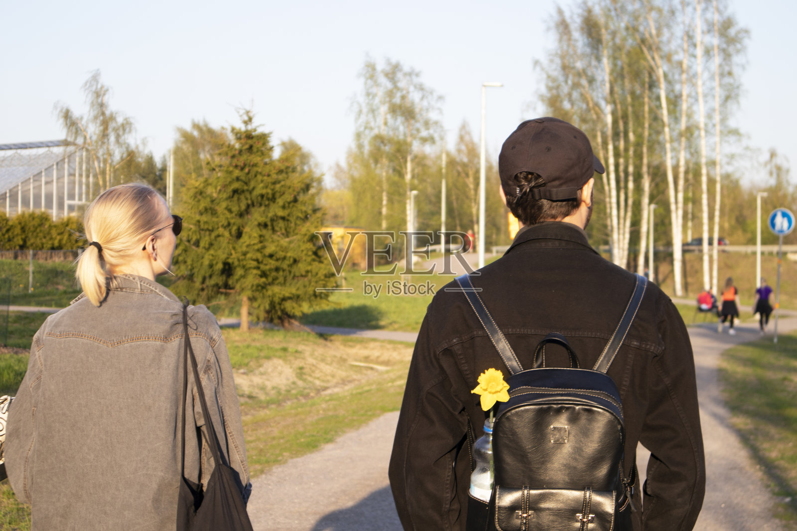 一对年轻夫妇在公园里散步，男人拿着花照片摄影图片