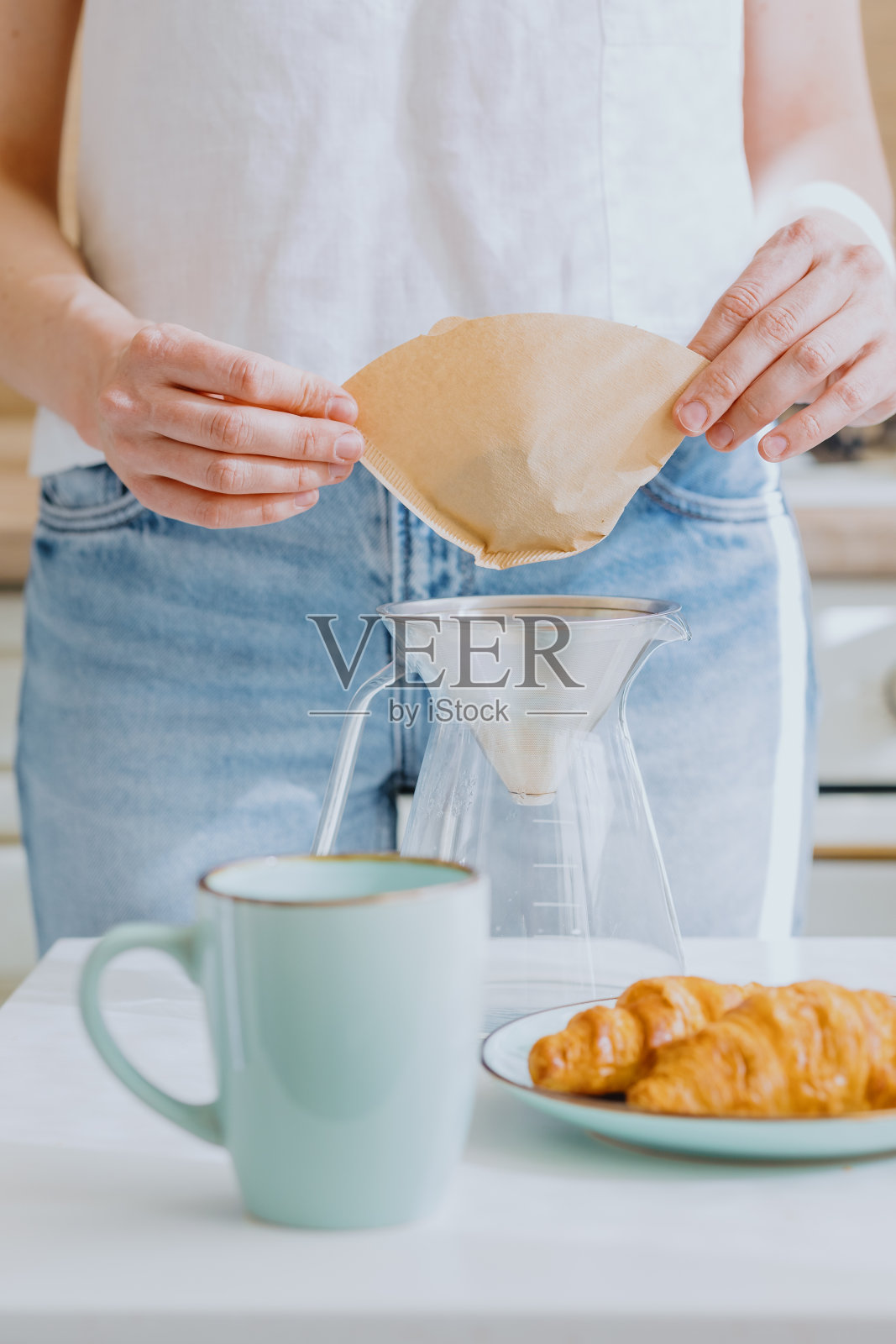 早上喝咖啡，欧洲女人煮咖啡喝，早餐吃牛角面包和咖啡照片摄影图片