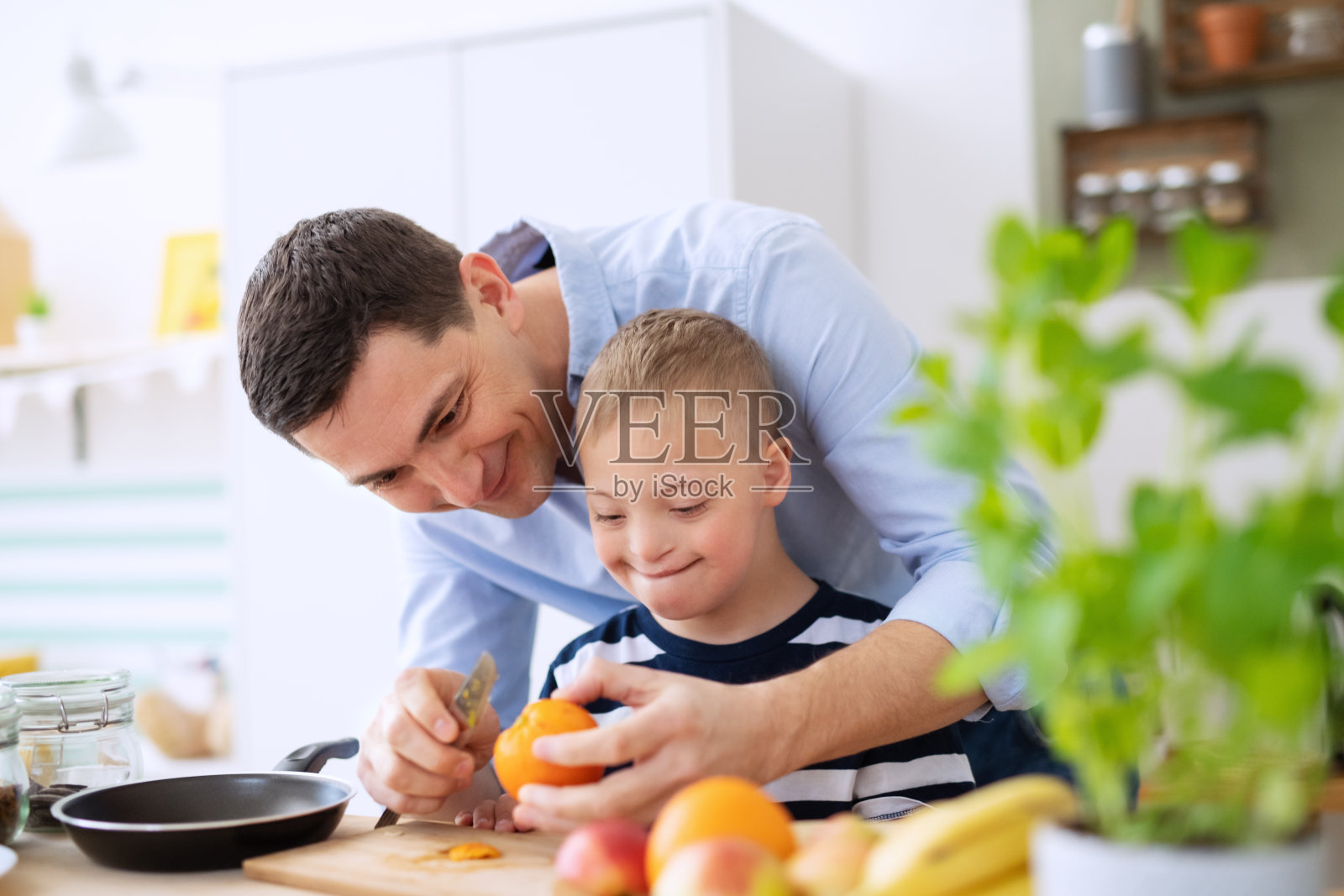 父亲和患有唐氏综合征的儿子在厨房里准备食物照片摄影图片