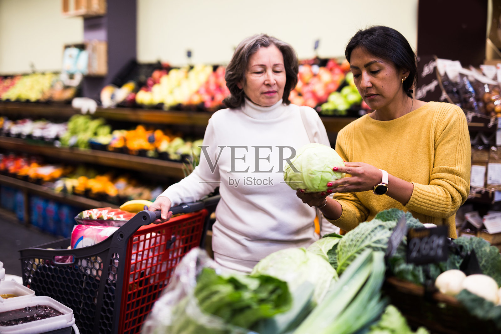 在商店蔬菜区挑选卷心菜的女性购物者照片摄影图片