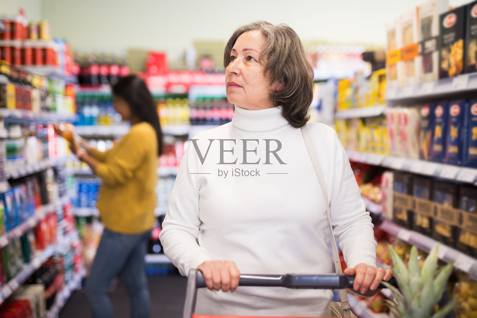 成熟积极的女人在商店货架上选择食品照片摄影图片