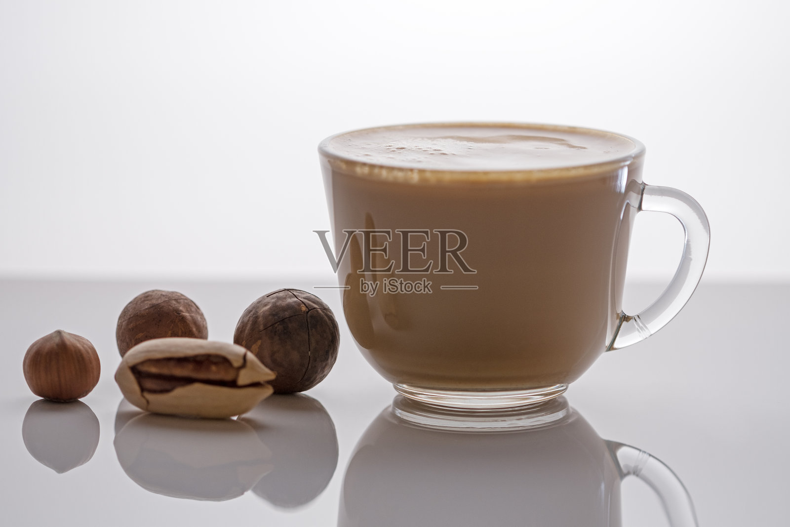 咖啡加牛奶和坚果。早上早餐概念。在厨房的一杯或一杯热咖啡卡布奇诺中加入牛奶照片摄影图片