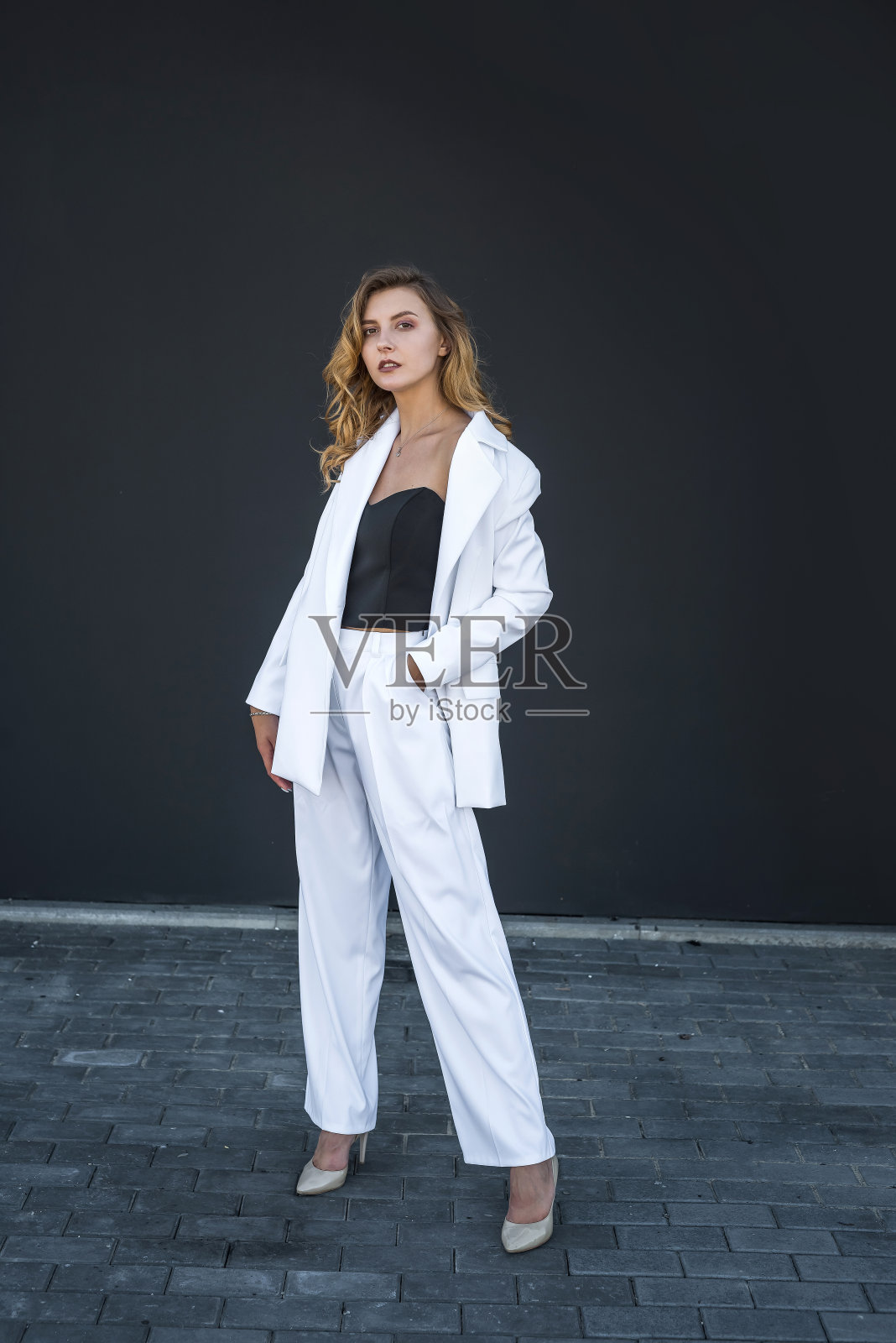 穿着白色套装的现代漂亮女人孤立在黑色背景上照片摄影图片