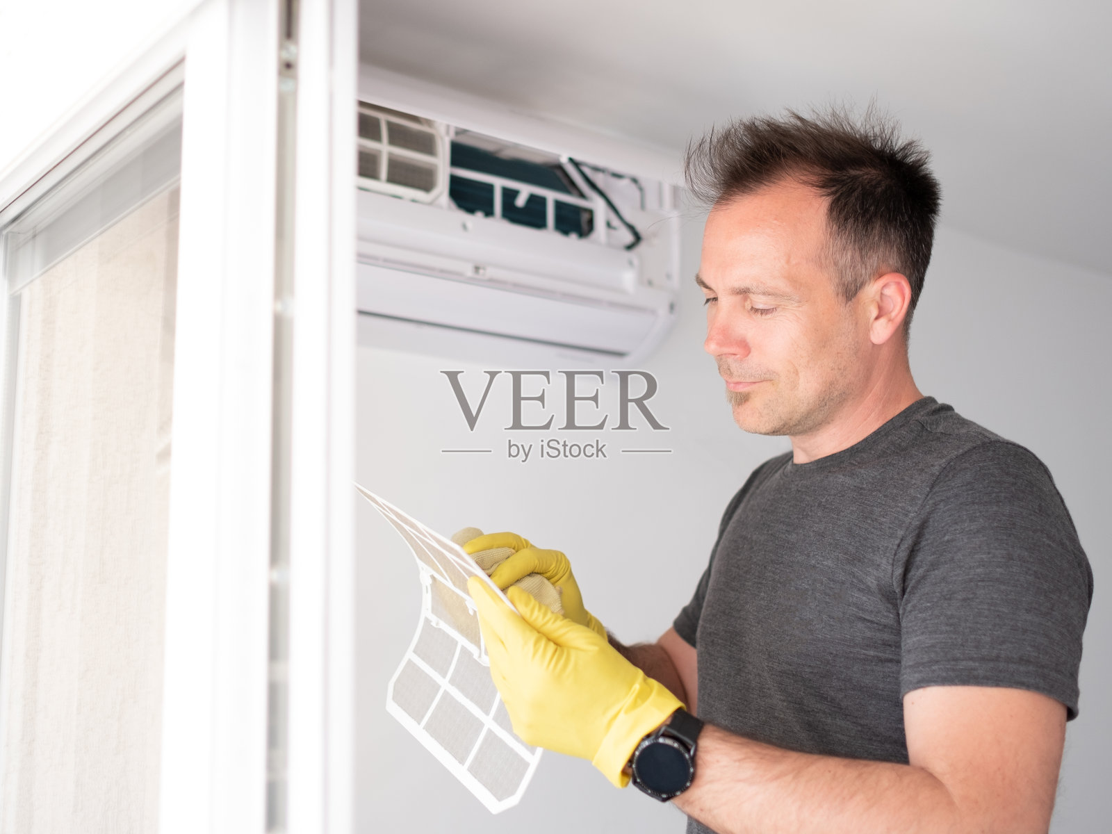 微笑着清洁室内空气过滤器的男子照片摄影图片