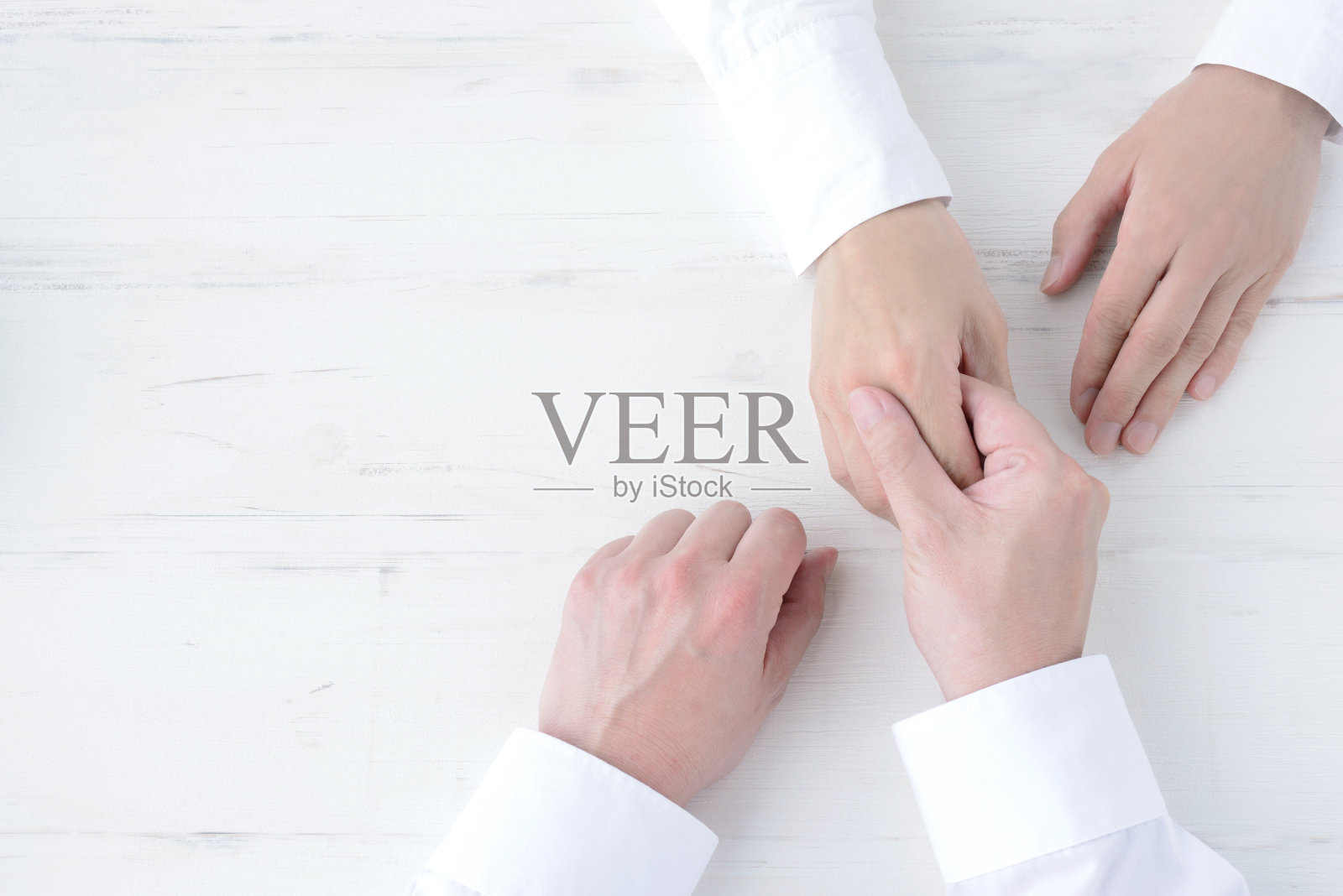 两人的手握在天然的白色木板上照片摄影图片
