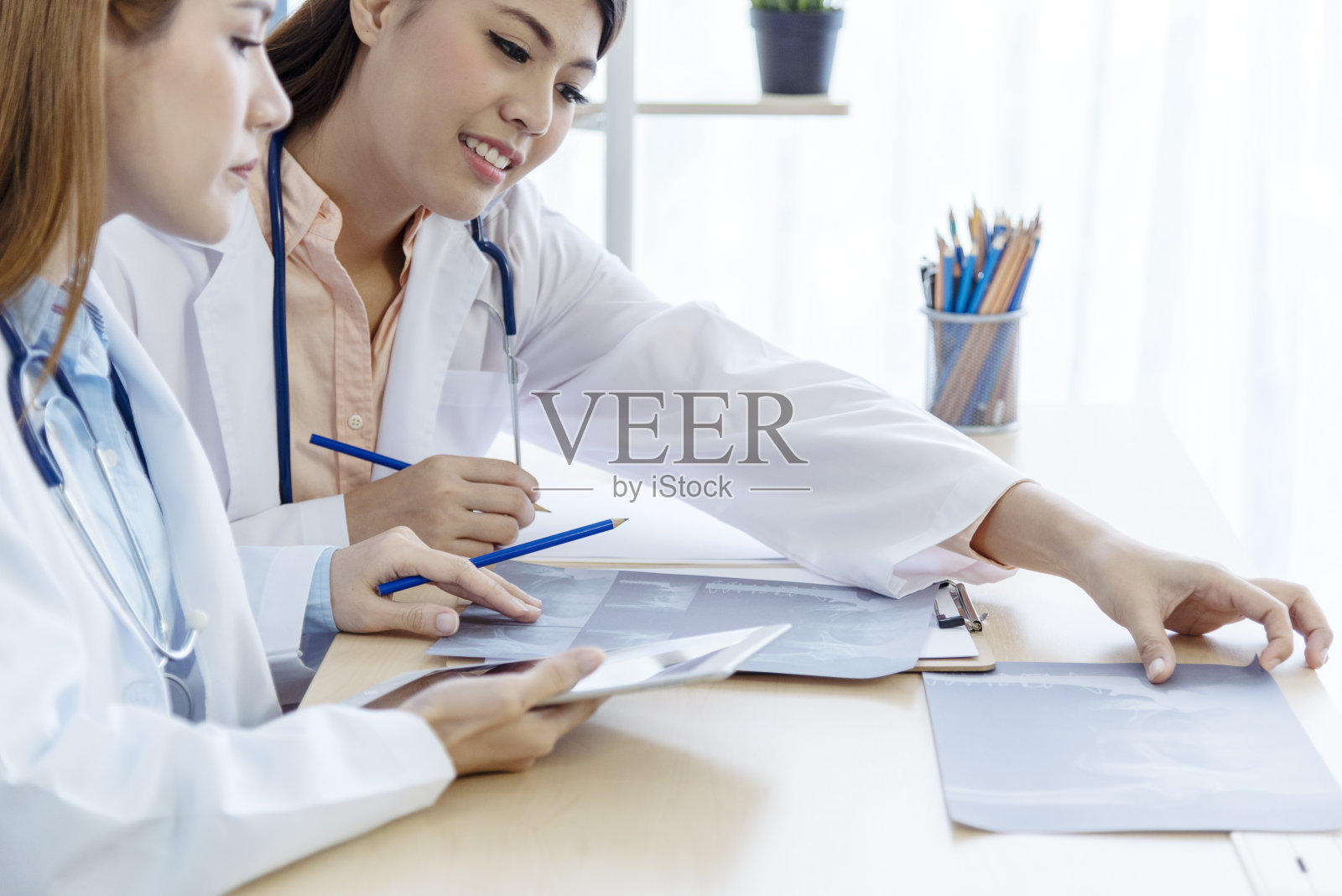 两位亚洲女医生讨论会诊室诊室看x光片咨询病人病情。亚洲医学实验室的年轻女性一起讨论医疗保健团队照片摄影图片