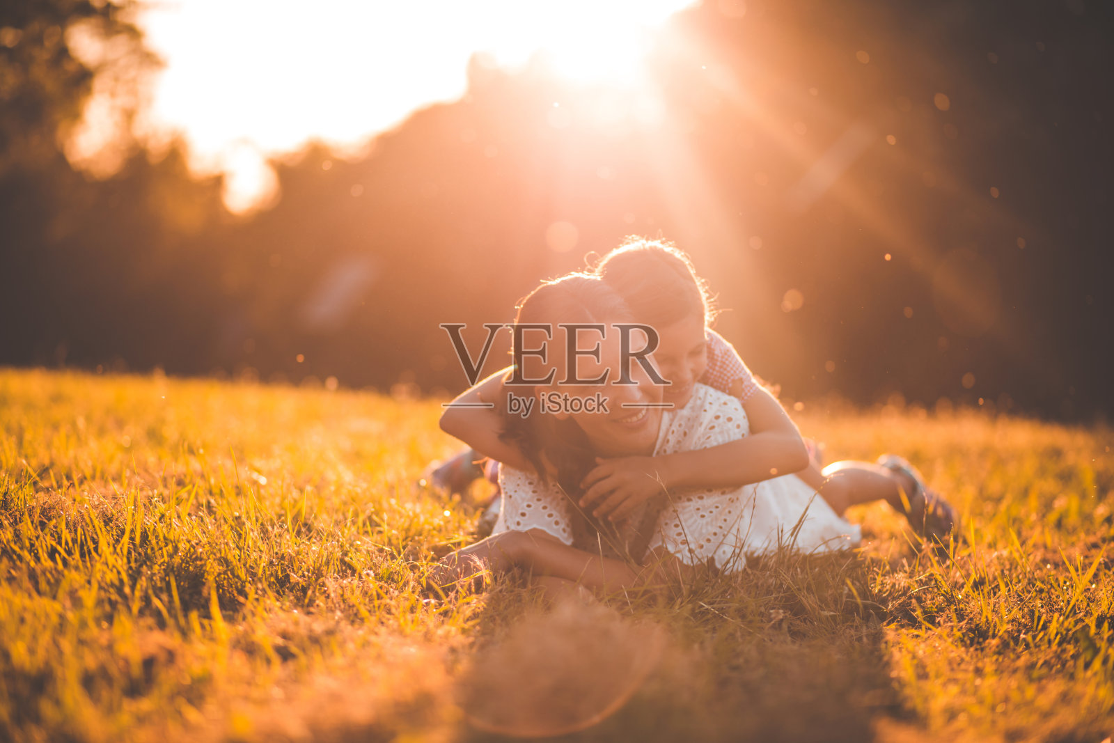 母亲和女儿躺在草地上。妈妈和孩子的肖像。照片摄影图片