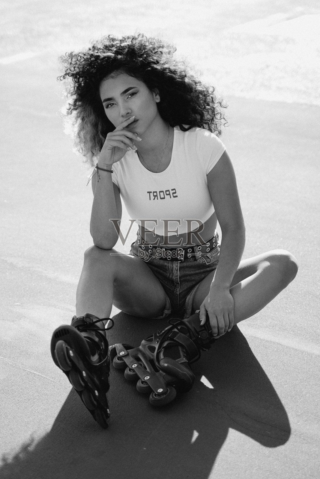 一个留着非洲式发型的女人在阳光明媚的夏日滑旱冰。照片摄影图片