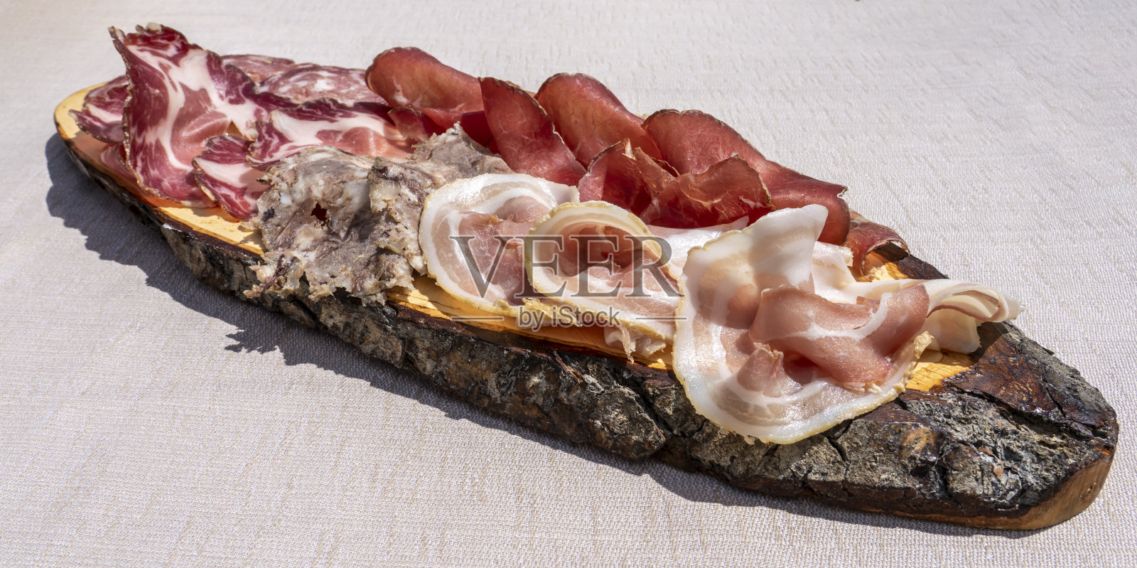 美味的砧板新鲜冷切木盘子。培根，意大利小杯，意大利腊肠和意大利熏牛肉。传统意大利山菜照片摄影图片