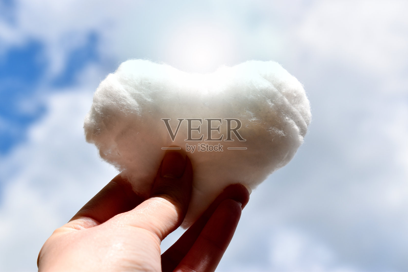 人的手在天空中握着一朵心形的云照片摄影图片