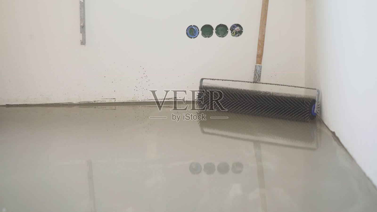 自流平地板上的木炭滚轮。木炭辊。耐磨地坪的工具。自流平环氧树脂。用水泥地面的混合物弄平照片摄影图片