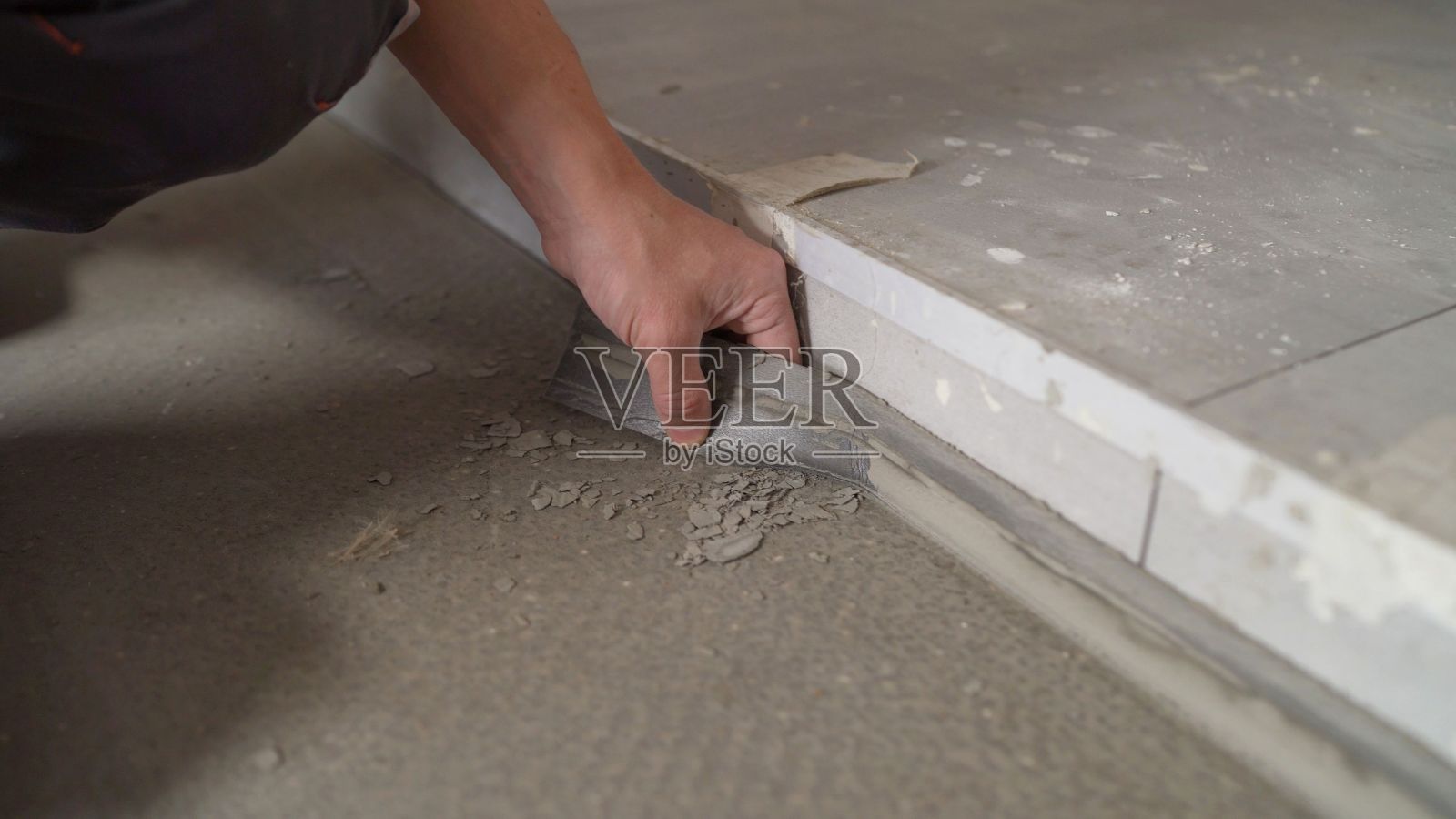 工人把胶带粘在房间周围的地板上。建筑的概念。安装底座在墙上。密封缝用施工胶带。照片摄影图片