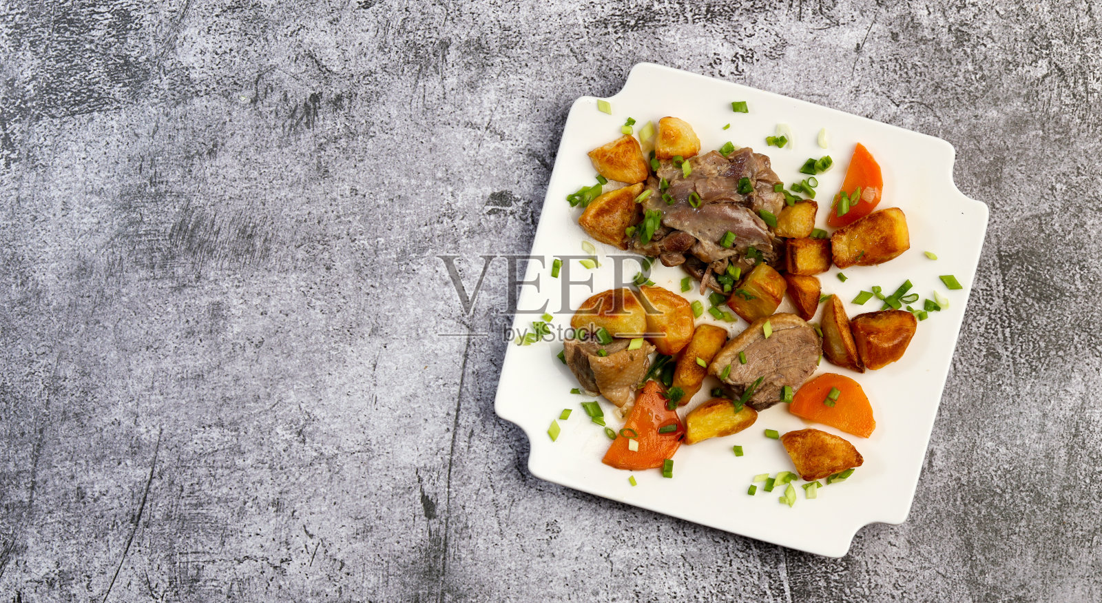 炖鸭配烤土豆和胡萝卜，以深灰色为底色照片摄影图片