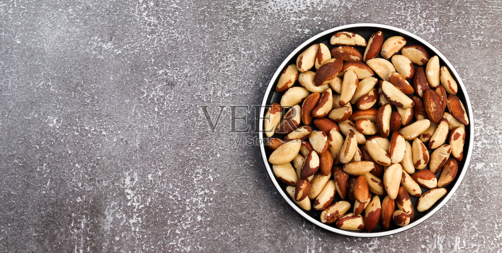 黑色背景下的圆盘子上的核桃照片摄影图片