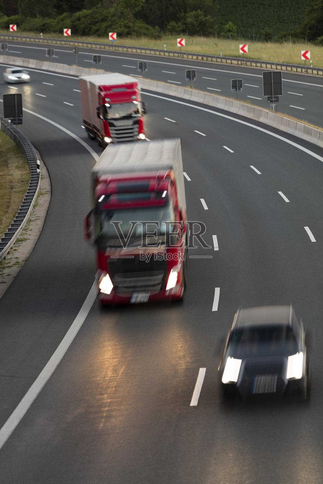 卡车和汽车在高速公路上加速在黄昏，重型货物运输在德国，鸟瞰图照片摄影图片