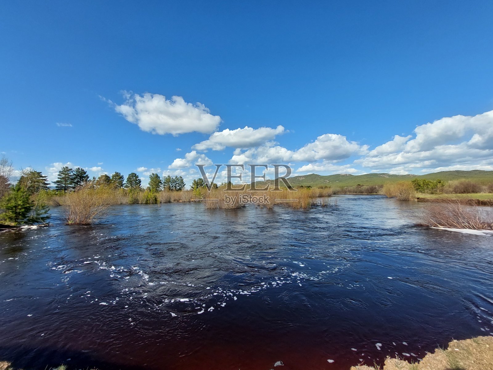 山峦和蓝天映衬下的春水河景照片摄影图片