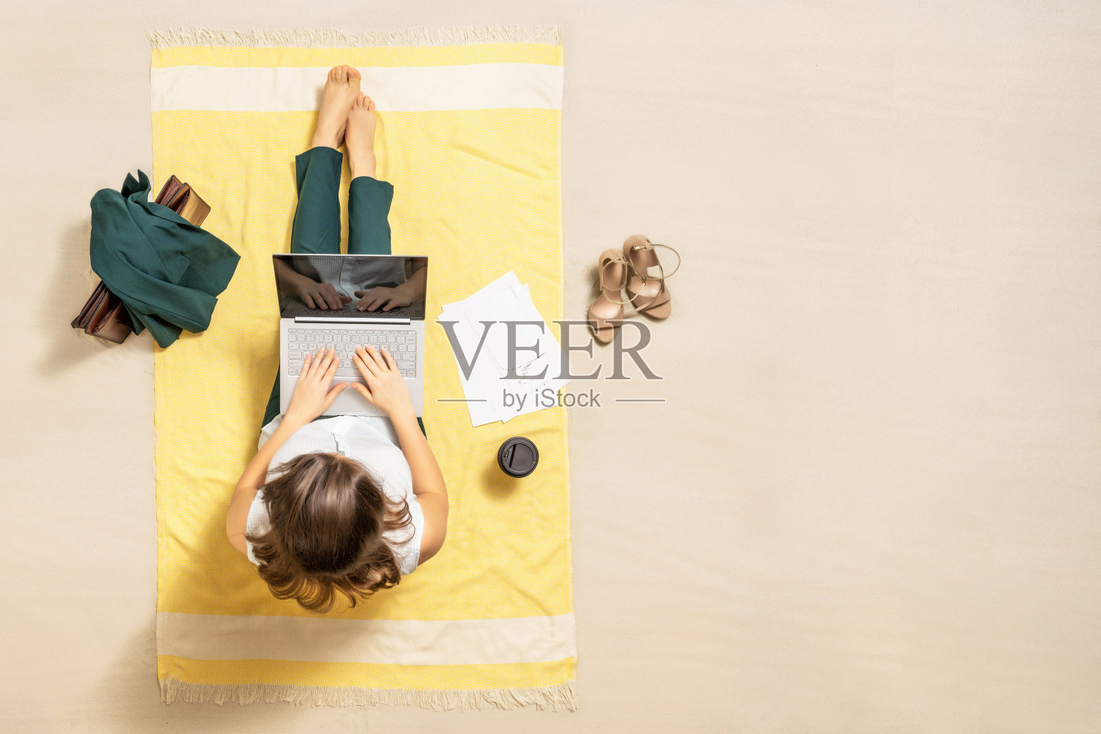 自由职业女商人穿着办公套装，坐在沙滩浴巾上喝着咖啡，用笔记本电脑处理图形和图表。午休时间。鸟瞰图照片摄影图片