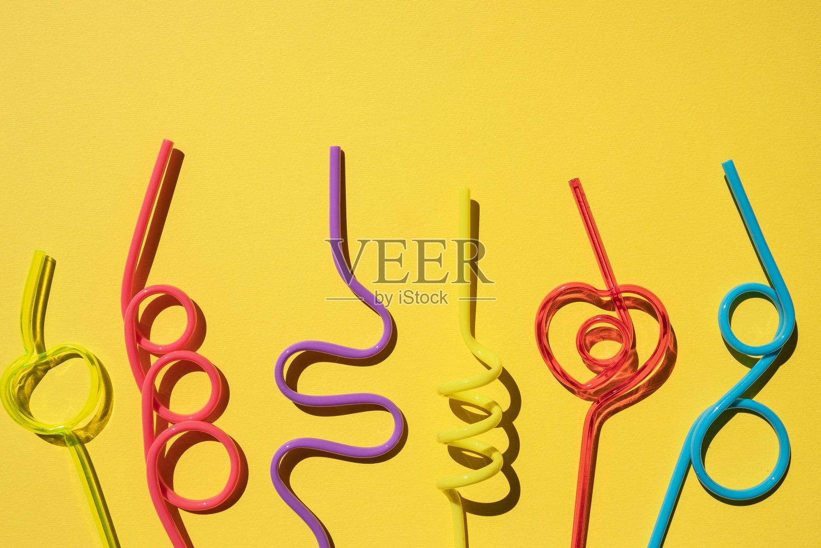 一套螺旋多色鸡尾酒管，孤立在黄色背景。饮料吸管。五彩缤纷的鸡尾酒。聚会、庆祝的概念。副本的空间。照片摄影图片
