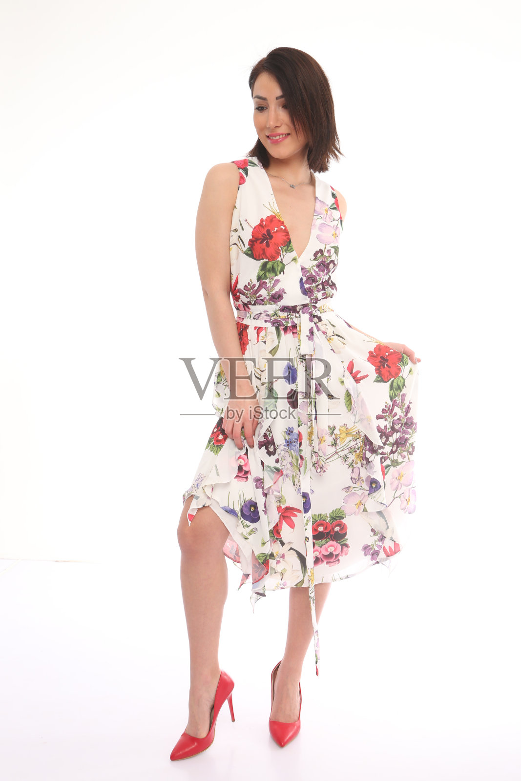年轻美丽的女人在休闲花卉图案的连衣裙前面的白色背景。夏季照片摄影图片