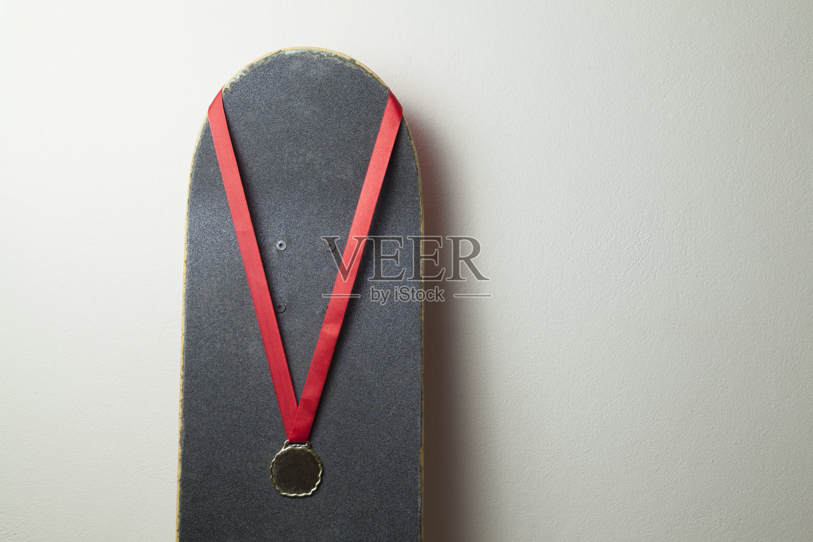 墙上有一块带金牌的滑板。照片摄影图片