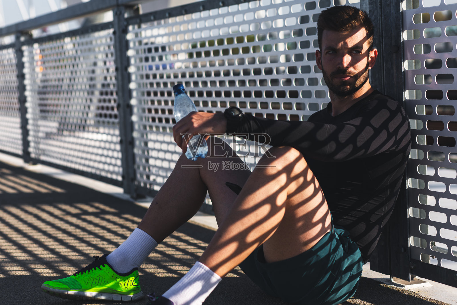 男跑步者在桥上晨练后休息。照片摄影图片