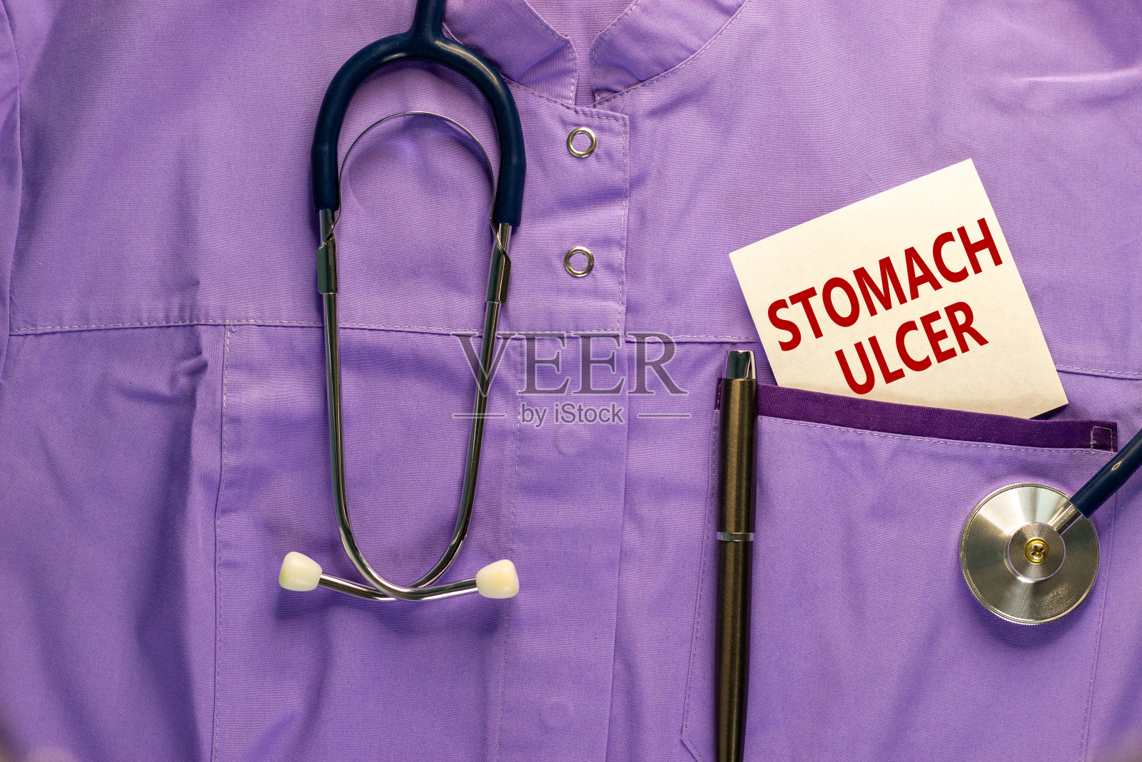 胃溃疡的象征。医疗制服，白色卡片上写着“胃溃疡”，金属笔和听诊器。医学和胃溃疡的概念。副本的空间。照片摄影图片