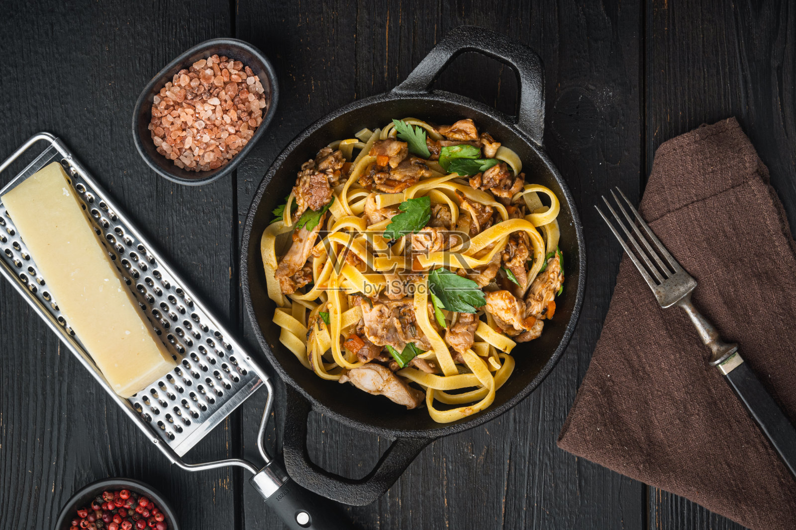 家常菜炖兔肉宽面条，放在煎锅或铁锅里，放在黑色木桌上，俯视图平铺照片摄影图片