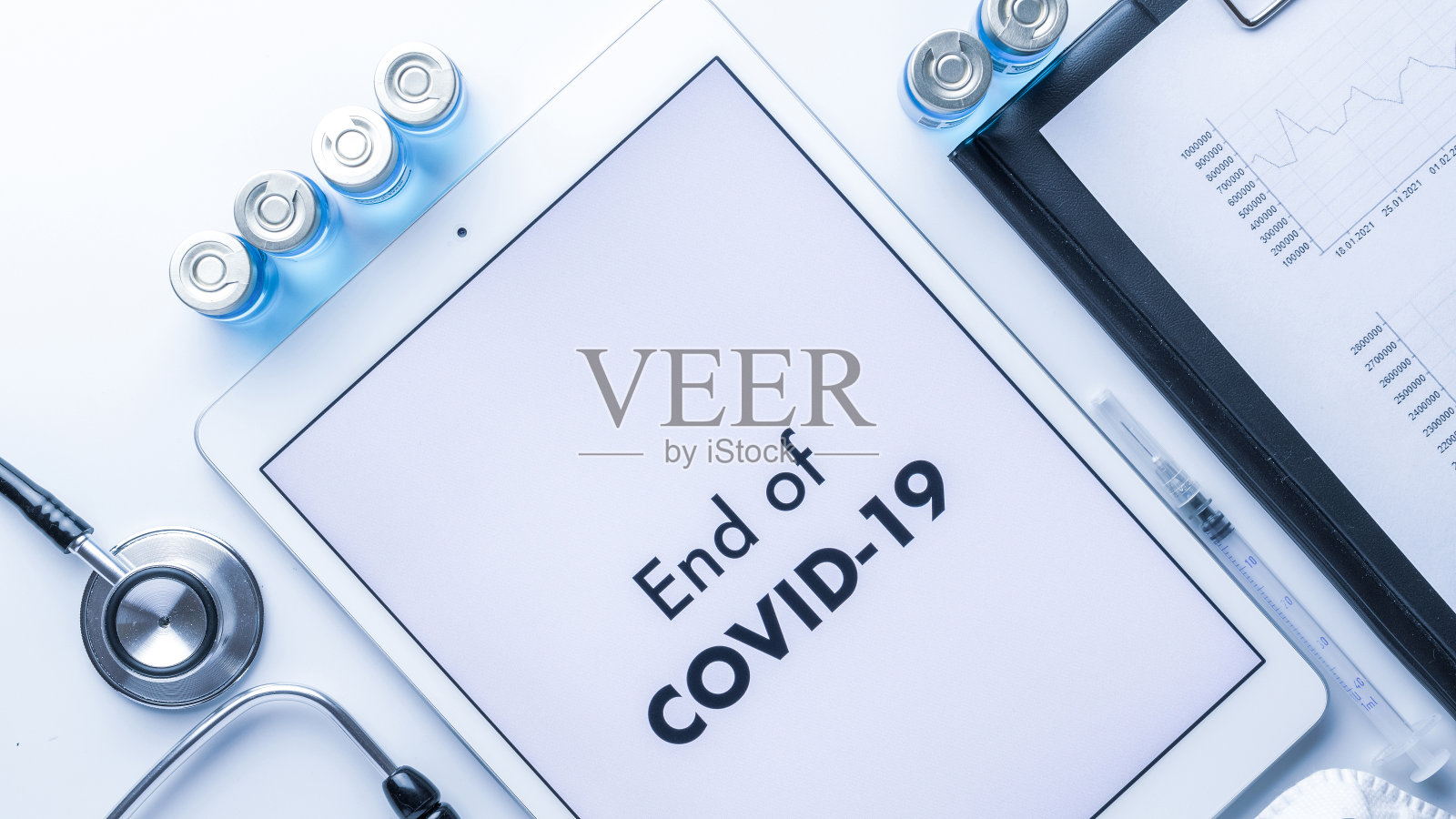 大流行结束了。医疗设备:医生听诊器、医院病历、带针注射器、屏幕上有文字的白色平板。2019冠状病毒病概念终结。照片摄影图片