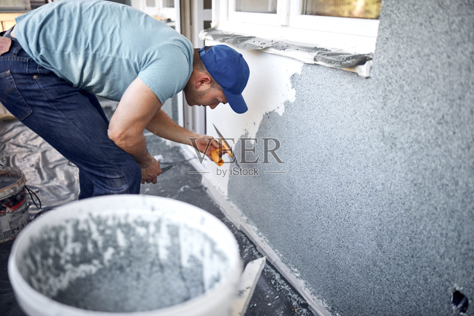 一个人在修房子的正面。照片摄影图片