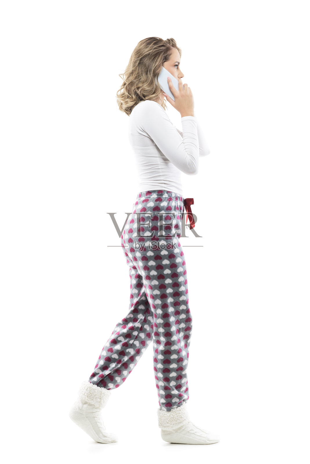 侧视图关注的女人穿着睡衣走路和打电话。照片摄影图片