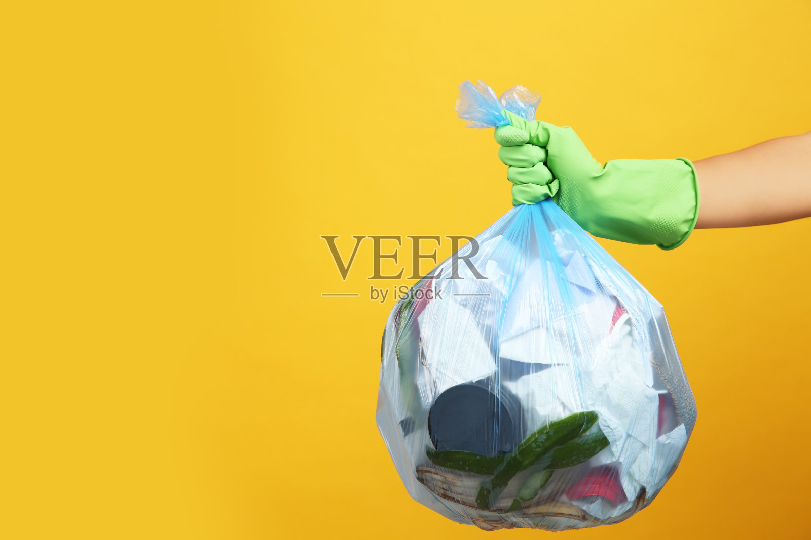 黄色背景上的女人拿着满满的垃圾袋，特写。空间的文本照片摄影图片