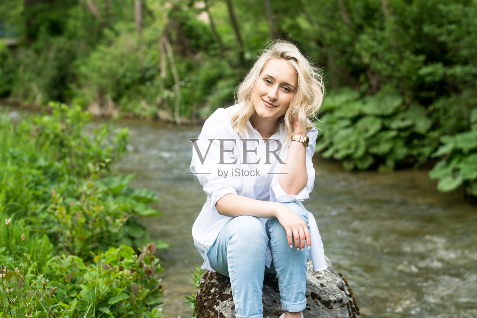 美丽的年轻女子坐在河边照片摄影图片