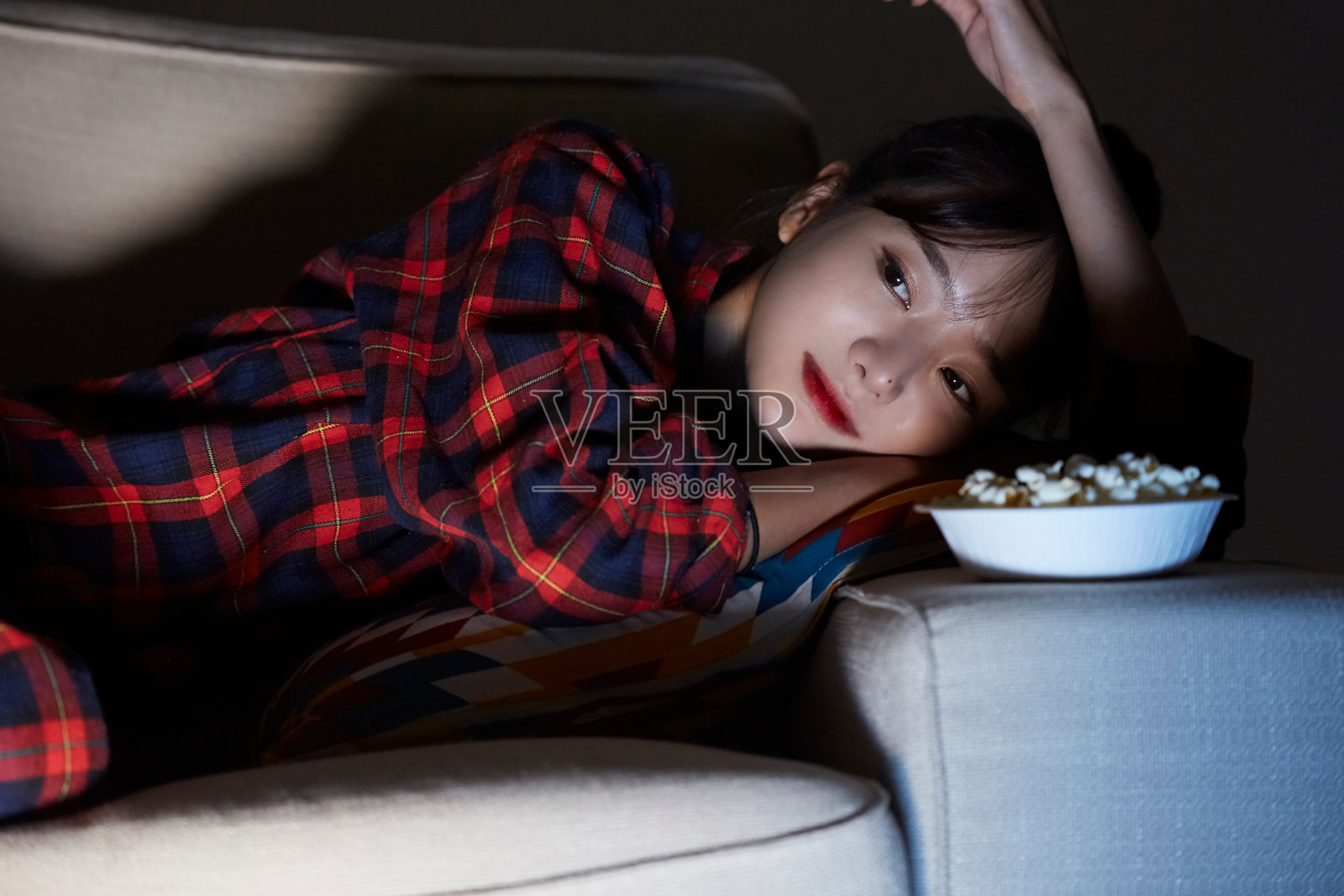 一个年轻的亚洲女人，在晚上看电影来放松照片摄影图片