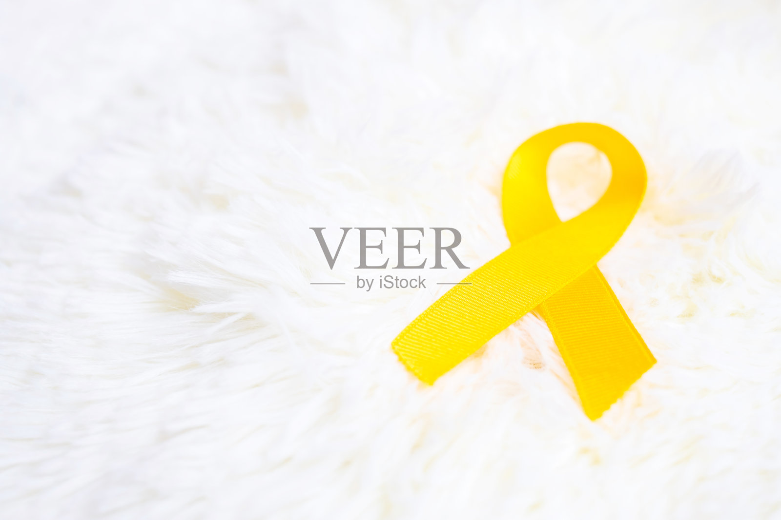 白色背景的黄丝带，用于支持生活和疾病的人。九月预防自杀日，肉瘤癌症和儿童癌症宣传月的概念照片摄影图片