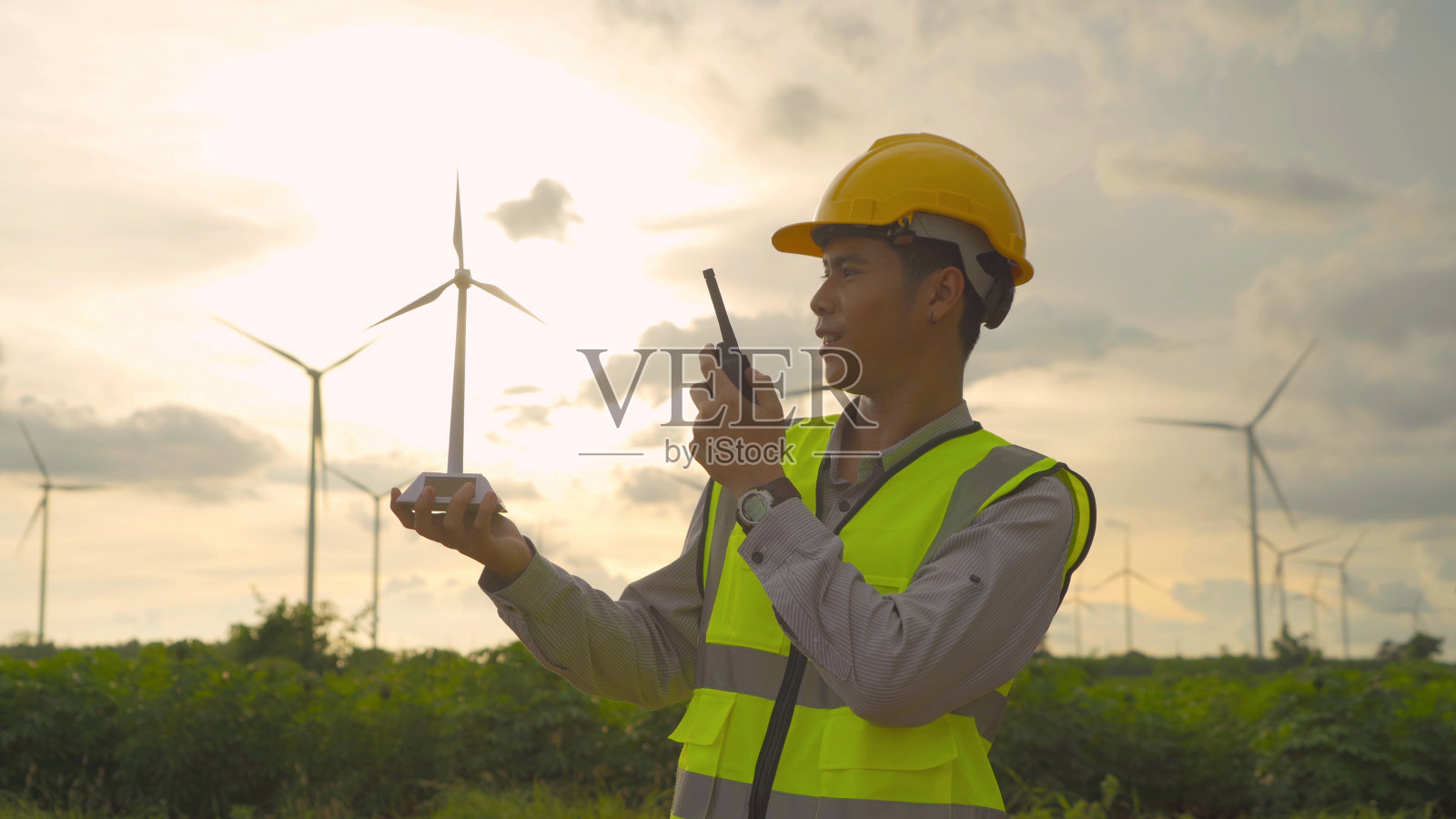 亚洲风车工程师的肖像，工人工作，手持一个现场的模型在风力涡轮机领域或农场，清洁能源。电动环保技术。工业自然环境。人照片摄影图片