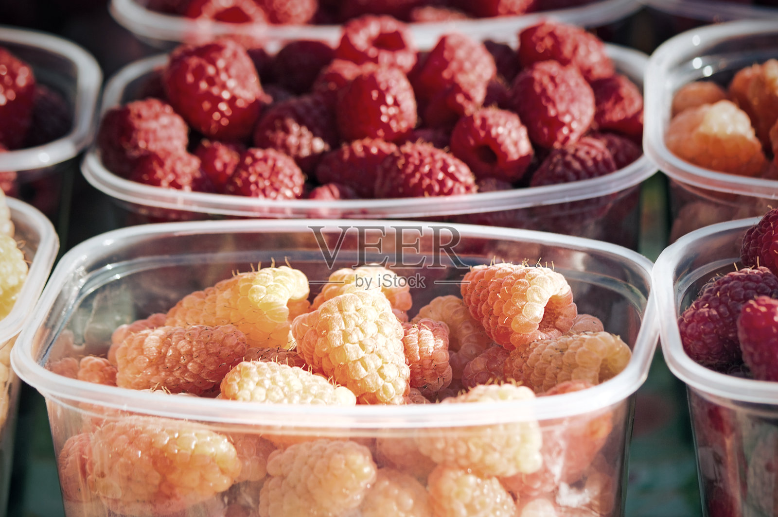 装在容器里出售的大熟覆盆子。照片摄影图片