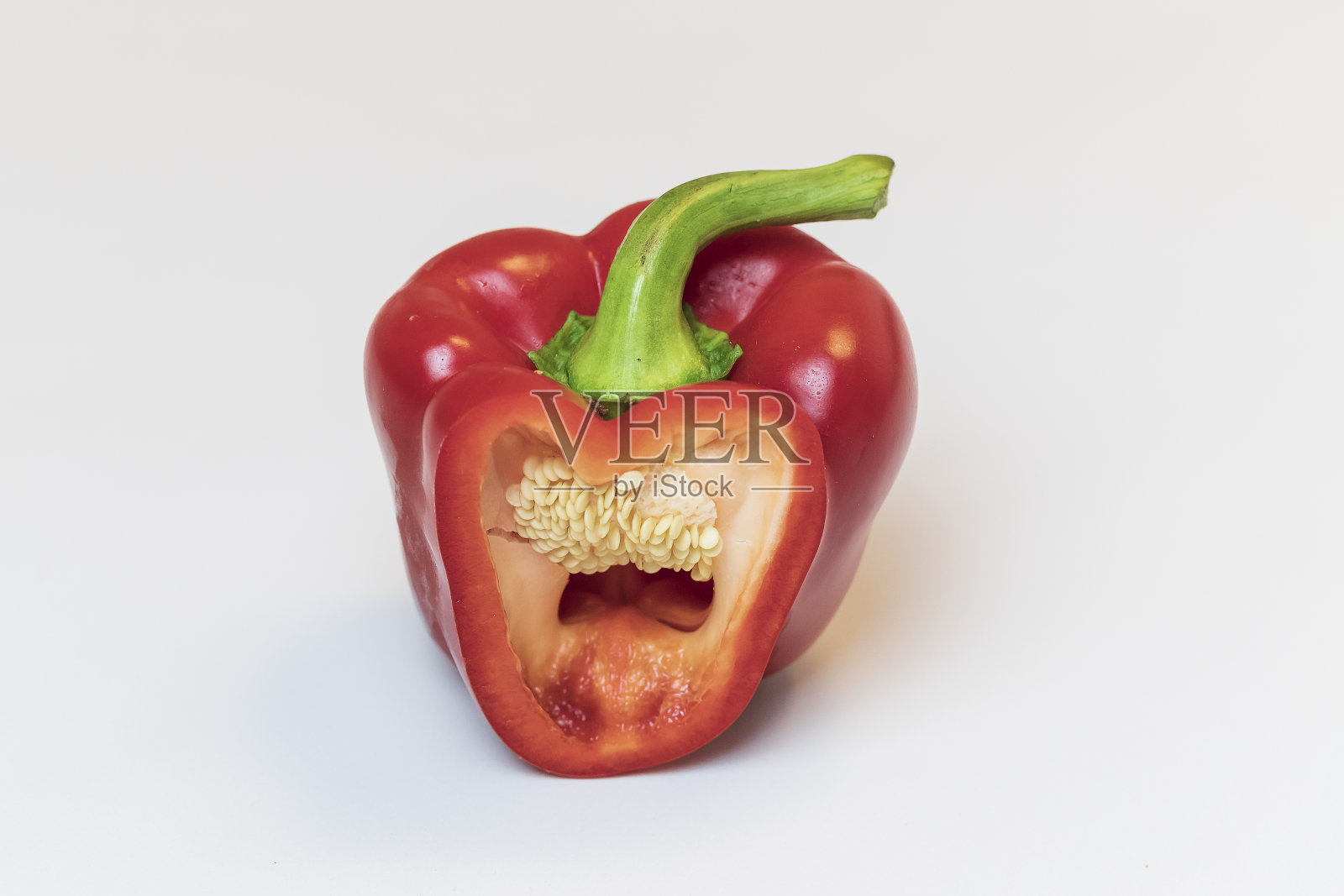 红辣椒，切一段，可以看到辣椒的结构。辣椒放在一个白色盘子上，照片的背景是白色的照片摄影图片