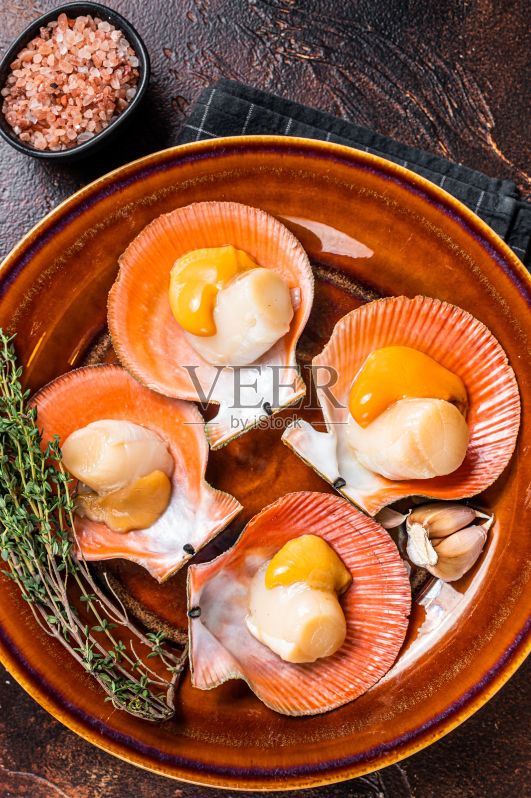 带百里香的乡村盘子里放着生扇贝。黑暗的背景。俯视图照片摄影图片