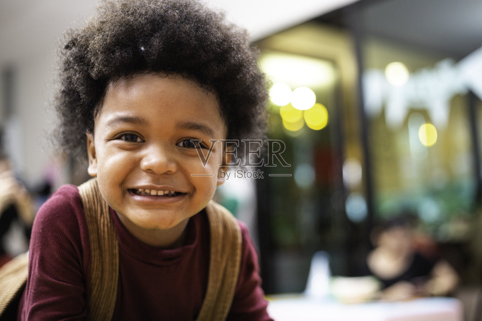 顽皮的黑人孩子的肖像微笑和做滑稽的脸，非洲裔美国男孩与非洲式头发看着相机照片摄影图片