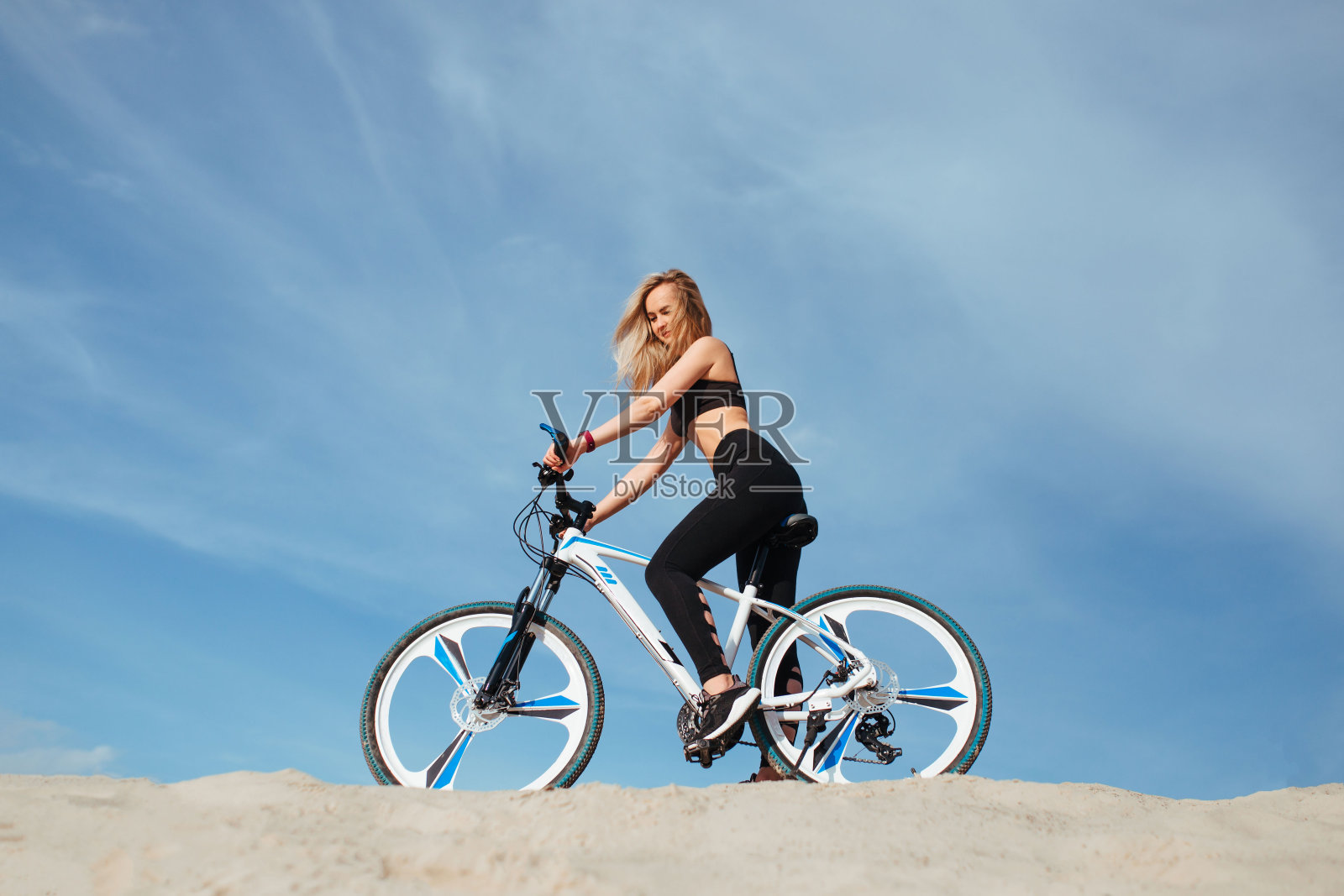 美丽的女人骑着自行车，背景是天空和沙滩照片摄影图片